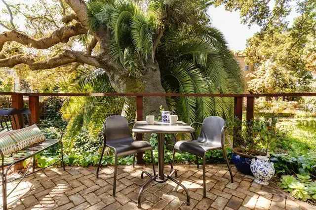 Brick patio with cafe table and chairs under a heritage oak and palm