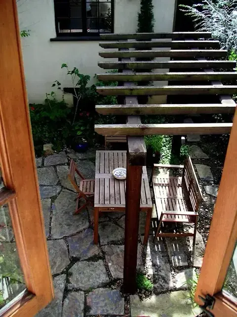 Flagstone patio with wood pergola and dining set viewed through French doors